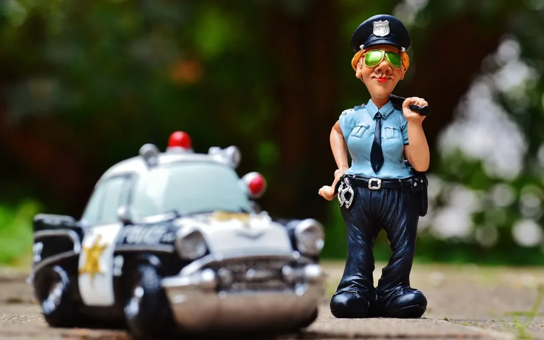 Figurine de policier avec voiture de police miniature en arrière-plan.