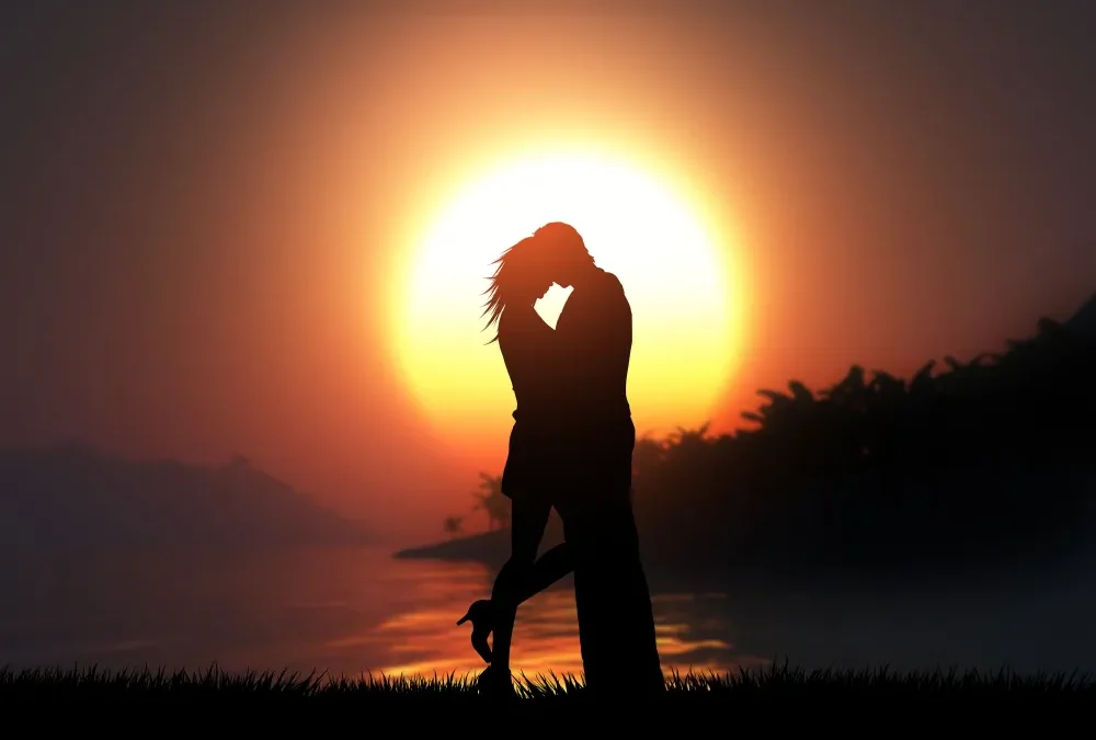 Couple s'embrassant au coucher du soleil près d'un lac.