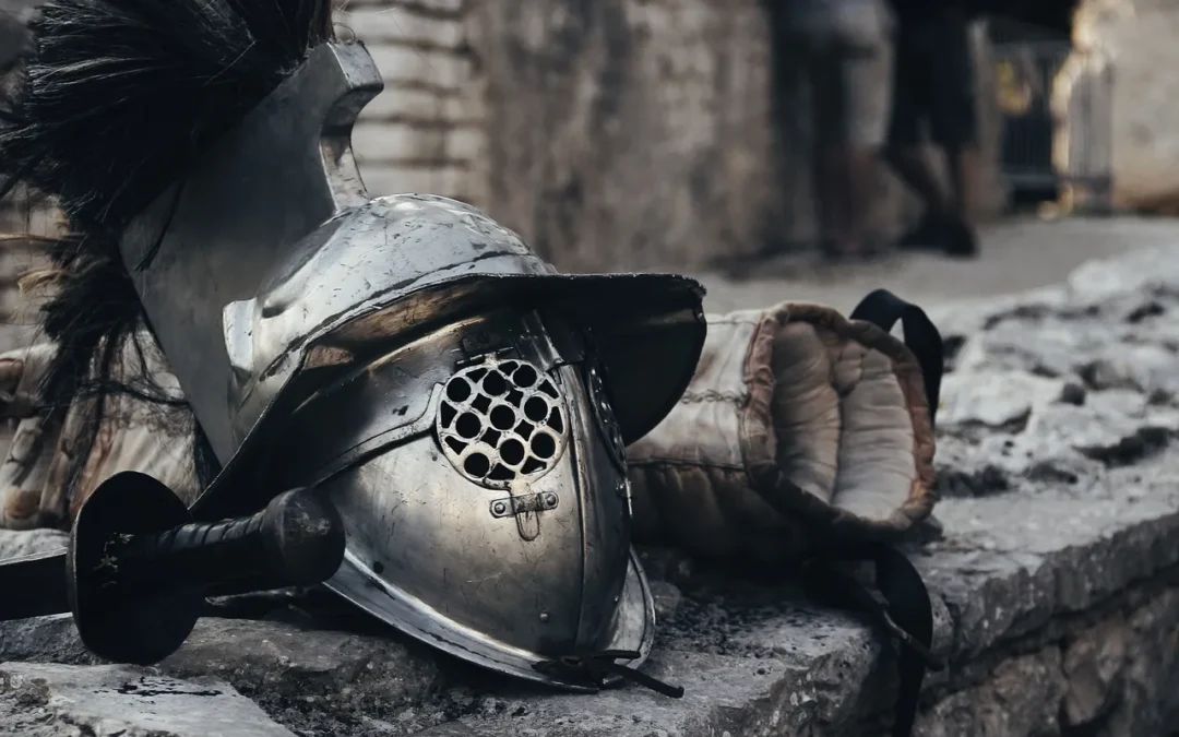 Casque et gantelet de gladiateur posés sur un mur de pierre.