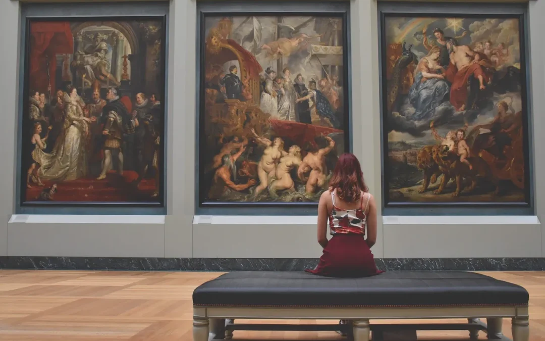 Une femme regarde trois grandes peintures classiques dans un musée.